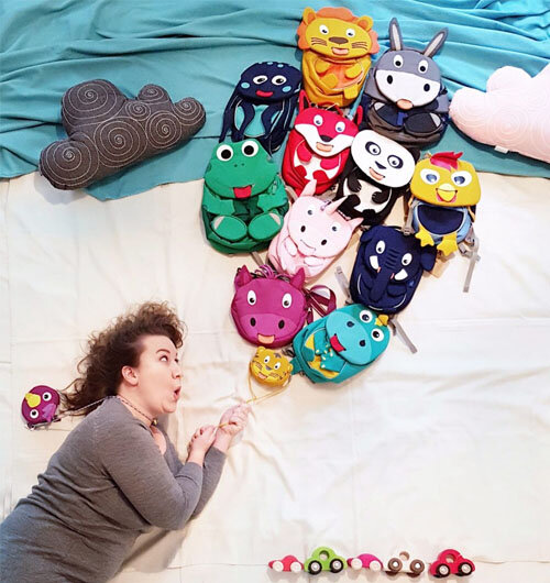 Flatlay mit Taschen von Affenzahn und Holzauto von Grimms Holzspielzeug als optische Illusion schwebt die Person an Luftballons aus Taschen über einer Straße