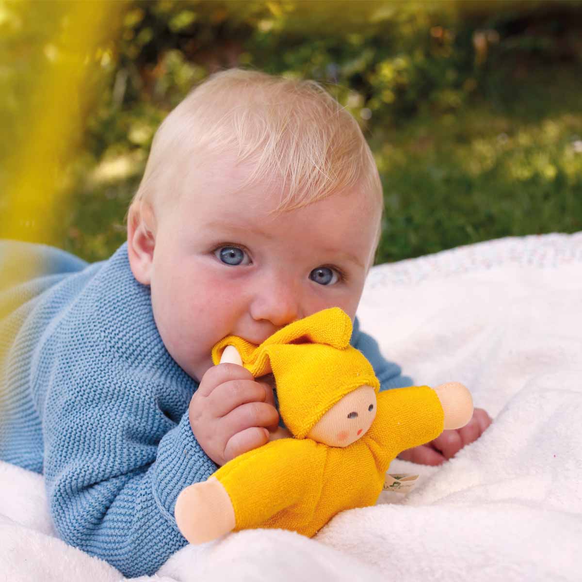 Baby liegt auf einer Decke und spielt mit dem Greifling Pimpel von Nanchen Natur