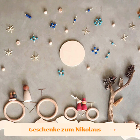 Flatlay mit dem Holzspielzeug von Grapat: Die Ringe und kleinen Figuren in einer Winterlandschaft mit Sternenhimmel und zwei Fahrrädern
